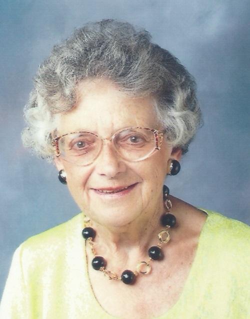 Foto einer älteren Dame mit Dauerwelle und großer Brille die freundlich in die Kamera lächelt