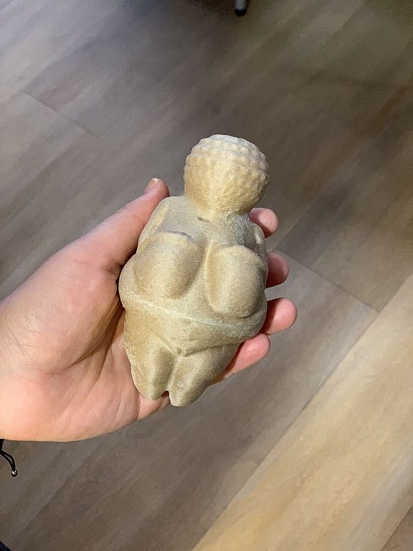 Hand hält Figur der Venus von Willendorf in der Hand