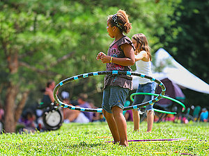 Kinder spielen im Park mit Hula Hoop Reifen.