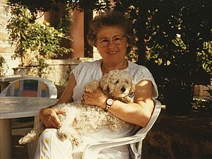 Dr. Gertraut Motzko in einem weißen Kleid im Sommer 1992. Auf ihrem Schoss liegt ein Hund.