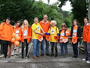 9 Personen in orangen und gelben Shirt hinter der Startlinie der Wanderung, Copyright: World Vision Österreich.
