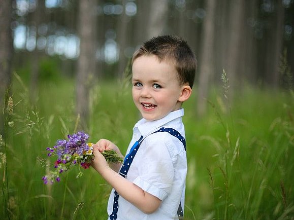 Emil steht mit einem kleinen Blumenstrauß in der Wiese