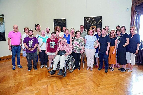 Gruppenbild von ca 25 Menschen, einige mit Rollstuhl und einige mit Langstock