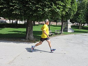 Laufender Mann mit gelbem T-Shirt und weißem Stock in der Hand