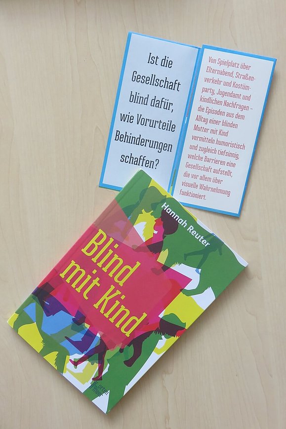 Das Buch "Blind mit Kind" liegt auf einem Flyer mit Zitaten aus dem Buch.