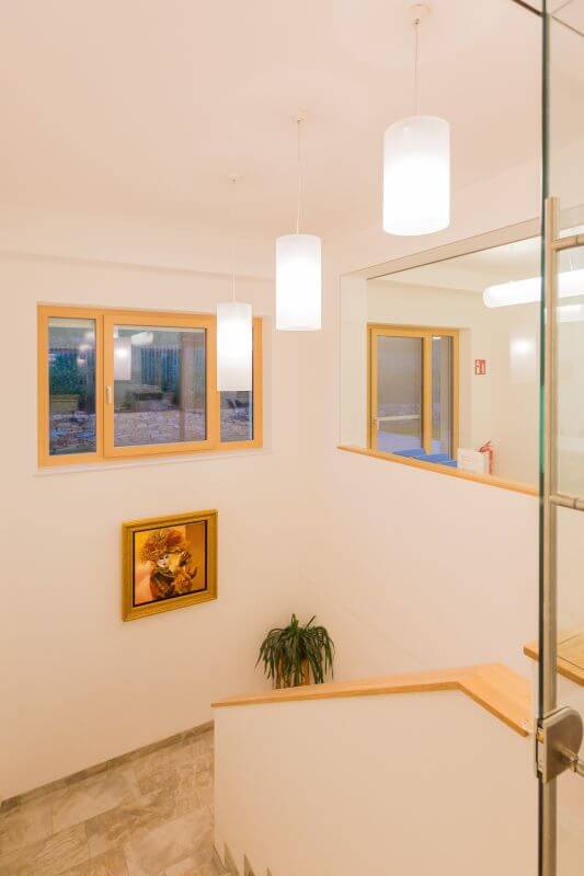 Drei vertikale Leuchten hängen im Stiegenaufgang von der Decke herab, Copyright: VIDEBIS.