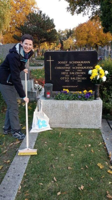 Alexandra Kleinheinz steht mit einem Besen bei einem Grab