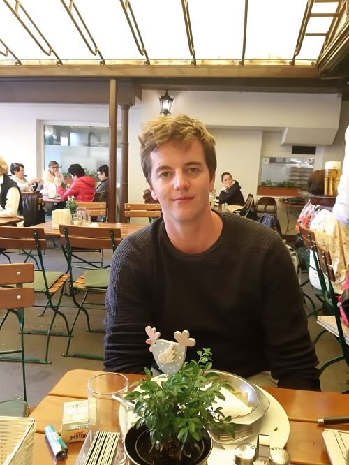 Maximilian Reutterer sitzt in einem Restaurant und lächelt in die Kamera. 