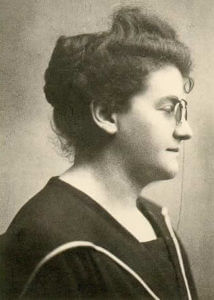 Profil einer Frau von der Seite in schwarz-weiß. Hat Dauerwelle und trägt eine Brille und schwarzes Oberteil