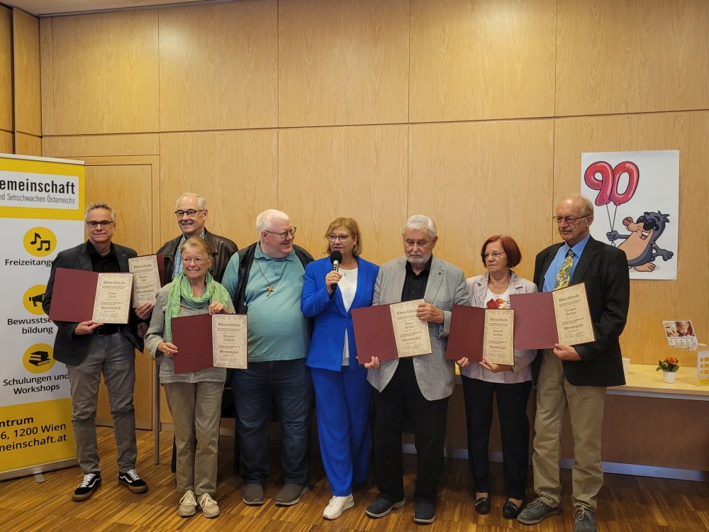 Feierliche Übergabe der Ehrungen Mehrere Personen stehen nebeninander und halten eine Urkunde in der Hand. In der Mitte steht eine Frau die moderiert und der Vorstandsvorsitzende Fürst