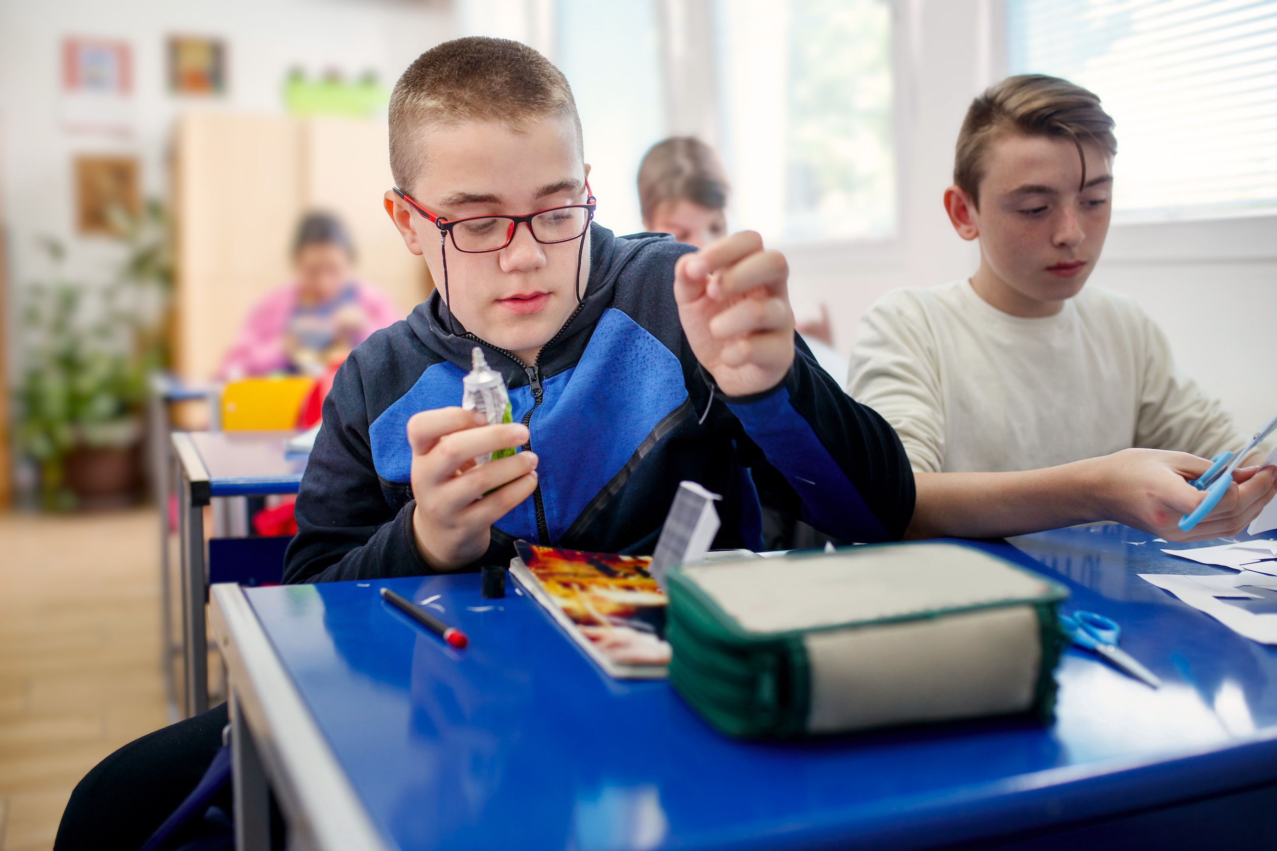 Bub mit Behinderung bastelt in der Schule mit anderen Kindern.