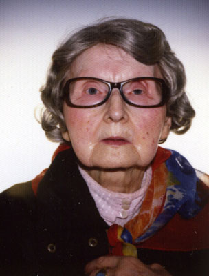 Eine ältere Dame mit großer Brille blickt ernst in die Kamera