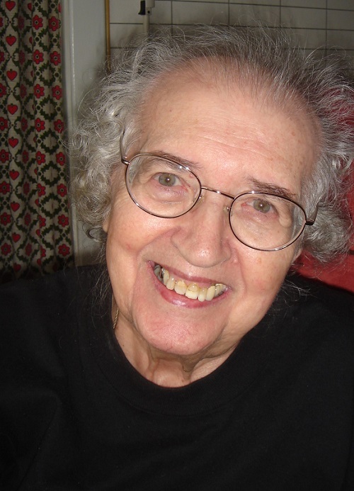 Eine ältere Dame mit Brille lächelt fröhlich in die Kamera