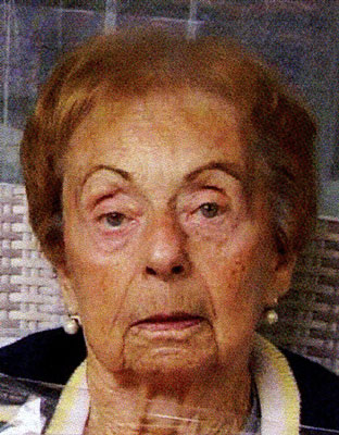 Eine ältere Dame mit Perlenohrringen und hellem Tuch um den Hals blickt gerade in die Kamera