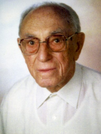 Foto eines älteren Herren mit Brille und weißem Hemd, der milde in die Kamera lächelt