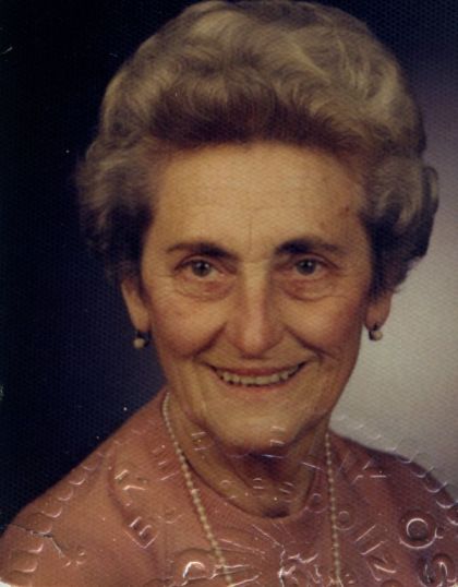 Portrait einer älteren Dame mit grauer Dauerwelle die freundlich lächelt.