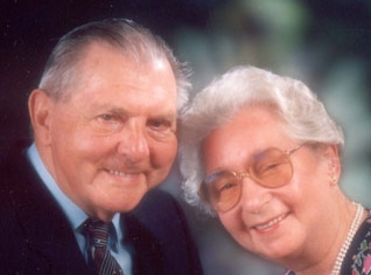 Gertrude und Ludwig Kucera Ein älteres Ehepaar sitzt einander zugeneigt und lächelt fröhlich in die Kamera