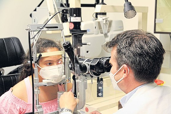 Arzt schaut durch Linse das Auge eines Mädchens an