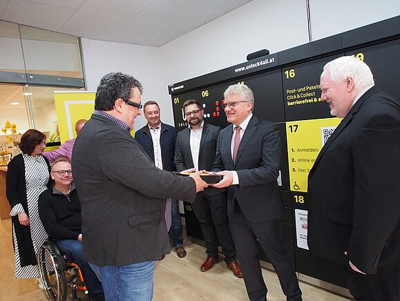 Mann übergibt Torte an anderen Herren vor Paketbox