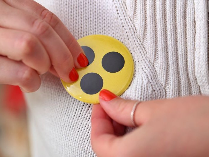 Button Gelber Button mit drei schwarzen Punkten