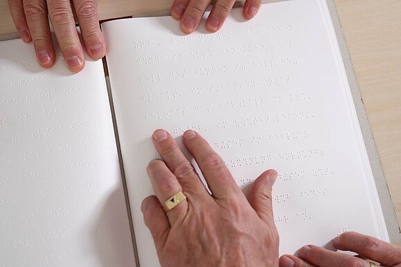 reiter_barrierefreie_printprodukte__c_Schedl_Hilfsgemeinschaft_A5 Hände ertasten Braillebuch