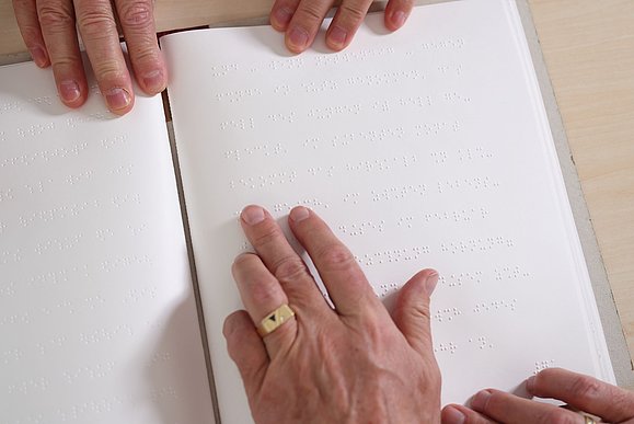 Hände ertasten Braillebuch