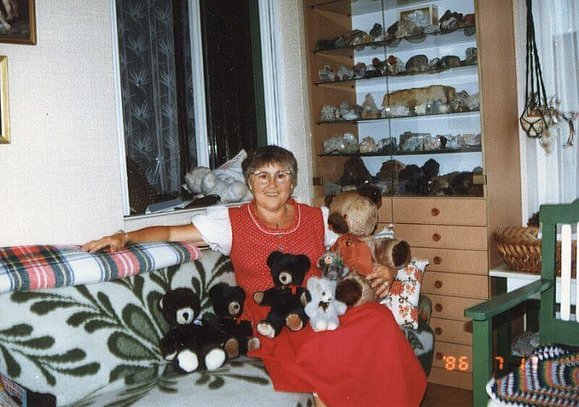 Gertraut Motzko in einem roten Kleid von ihren Teddybären umgeben.