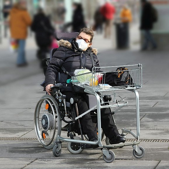 Rollstuhlfahrerin auf einer Einkaufsstraße