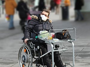 Rollstuhlfahrerin auf einer Einkaufsstraße