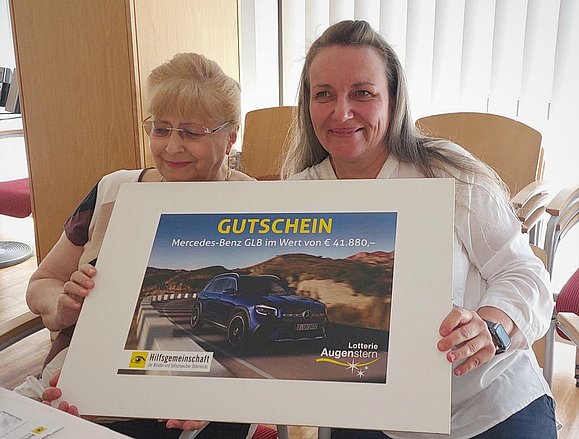 Ältere und jüngere Frau halten Gutschein mit Bild von Auto