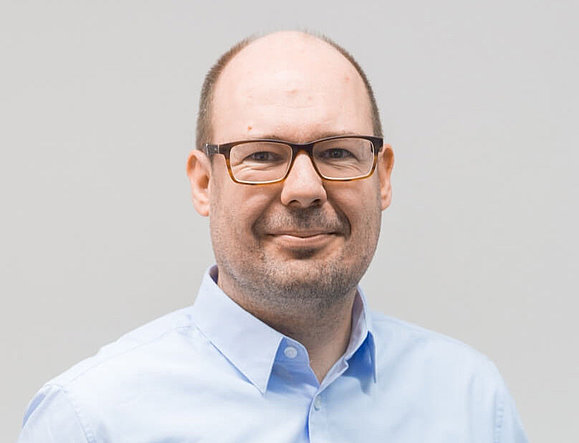 Ein Mann mit Brille lächelt in die Kamera.