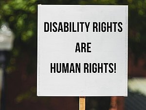 Protestschild vor Baum: "DISABILITY RIGHTS ARE HUMAN RIGHTS!"