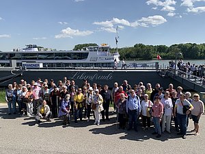 Gruppe von ca 50 Menschen vor Fähre bei sonnigem Wetter