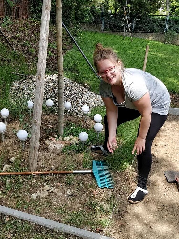 Junge Frau bei der Gartenarbeit lächelt in Kamera