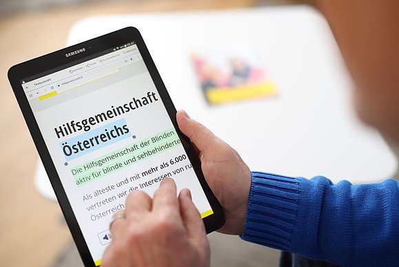 Person bedient Tablet mit Website der Hilfsgemeinschaft