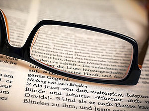 Brille liegt auf einem offenen Buch