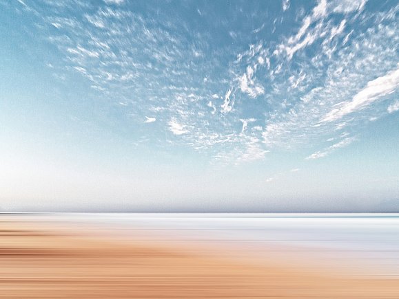 Ein hellbrauner, einem Strand ähnelnder, Untergrund trifft auf einen hellblauen Himmel mit weißen Wölkchen.