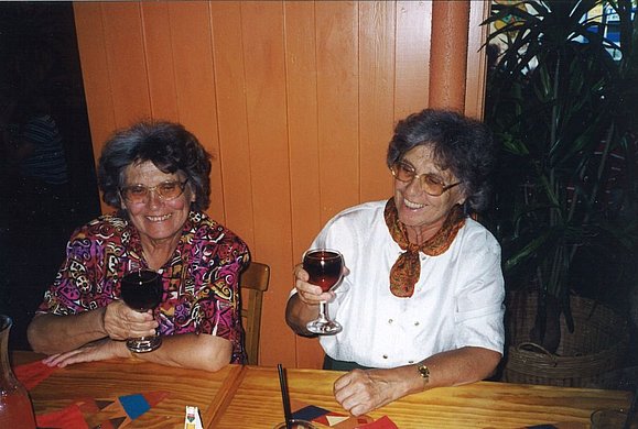 Zwei ältere Frauen - Zwillinge heben lächelnd ihr Weinglas