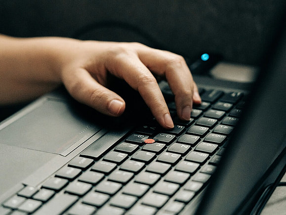 Wir suchen Assistenz in der Beratung. Foto von Szabo Viktor auf Unsplash Eine Hand liegt auf der Tastatur eines schwarzen Laptops.