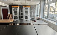 Großer Raum mit vielen Tischen und zwei Telefonzellen