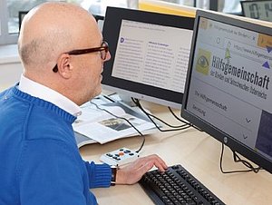 Ein Mann arbeitet an einem für sehbehinderte Menschen ausgestattetem Arbeitsplatz.