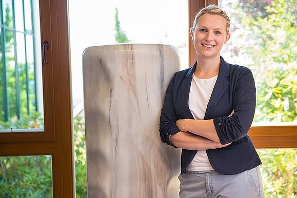 Birgit Ofenböck lehnt sich mit ihrer Schulter an eine Marmorsäule.