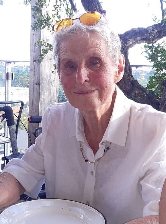 Eine Frau mit grauen Haaren lächelt in die Kamera