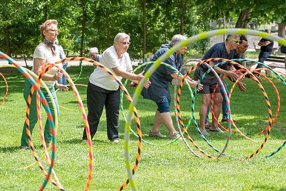 Menschen spielen im Park mit Hula-Hoop Reifen.