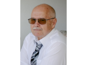 Ein Poritrait von einem Mann mit Sonnenbrille und Hemd + Krawatte.