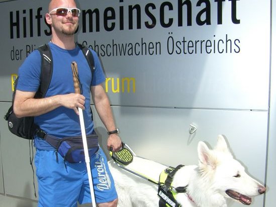 Julian Alexander mit seinem Blindenführhund Dimo vor dem Eingang der Hilfsgemeinschaft.