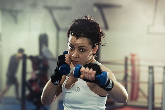 Frau boxt, Boxring im Hintergrund