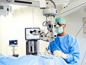 Ein Arzt operiert eine Person, die am Op-Tisch liegt, am Auge