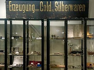 Glasregale mit Schild: Erzeugung von Gold & Silberwaren