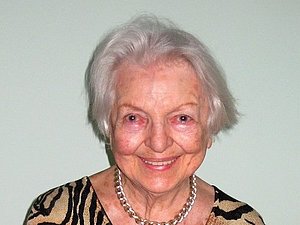 Eine ältere Dame lächelt fröhlich in die Kamera